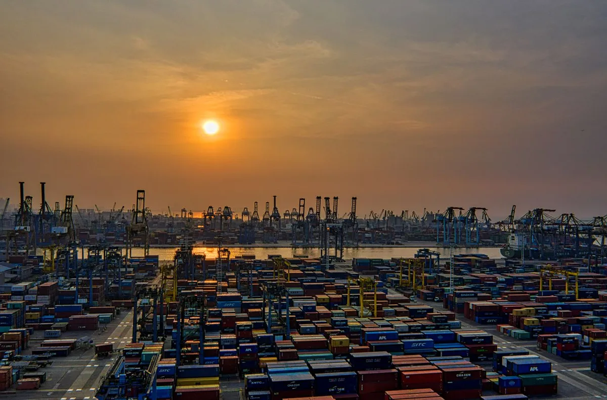 Cảng biển với các dãy container và cần cẩu dưới nắng chiều